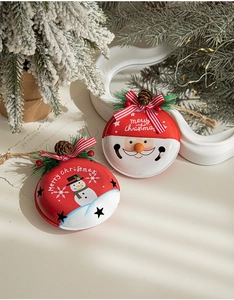 Detail of Christmas metal bell ornaments with Santa and Snowman motifs and pine cones