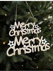 Detail of wooden Merry Christmas hanging signs with white stars on a green tree