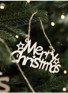 Detail of wooden Merry Christmas sign with stars hanging on a festive Christmas tree
