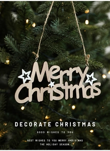 Detail of wooden Merry Christmas hanging ornament with white stars on a festive tree