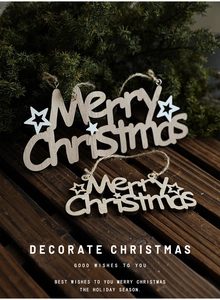 Close-up of laser-cut wooden Merry Christmas ornaments with stars on pine branches