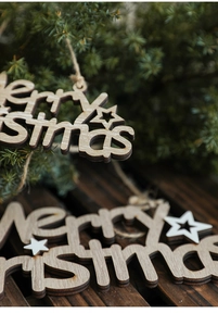 Detail of laser-cut wooden Merry Christmas ornament with white star and rustic twine