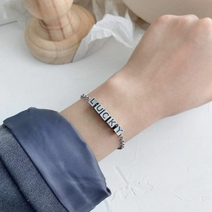 Macro detail of silver lucky charm bracelet with rectangular beads on wrist