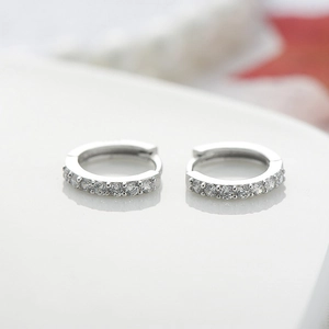 Vista macro di orecchini huggie in argento sterling con pavé di zirconi brillanti