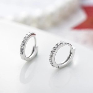 Vista macro di orecchini huggie argentati con pavé di zirconi trasparenti
