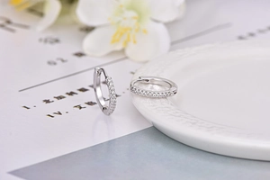 Macro di orecchini huggie in argento con zirconi cubici su uno sfondo bianco pulito