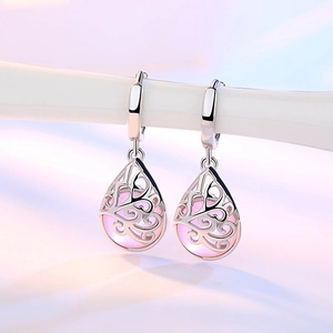 Silver drop earrings with pink moonstone and intricate filigree patterns on white stand