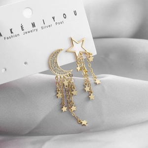 Macro detail of asymmetric star and moon tassel earrings with gold finish and zircon