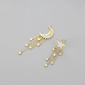 Detailed close-up of asymmetric gold moon and star tassel earrings with inlaid accents