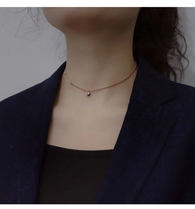 Close-up of a rose gold beaded choker necklace with a central round ball pendant on a model