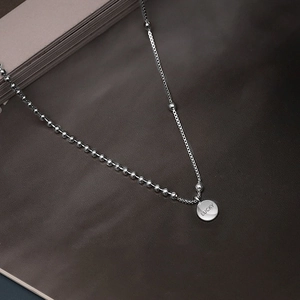 Silver ball chain necklace featuring a flat round pendant engraved with Lucky text