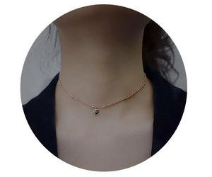 Close-up of rose gold bean necklace with asymmetric bead chain on model neck