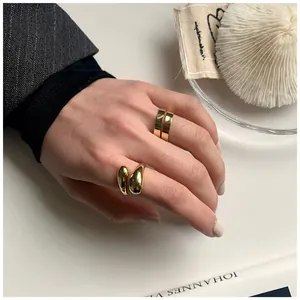 Close-up of gold-plated spiral ring and teardrop ring on hand with elegant office background
