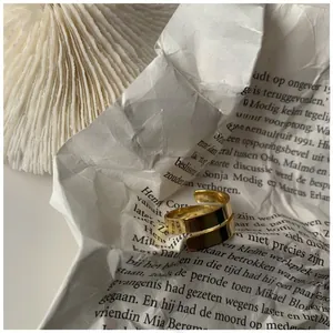 Detail of a polished double spiral gold ring placed on a textured newspaper background