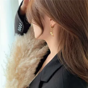 Close-up of elegant gold star tassel earrings worn by a model with a stylish aesthetic