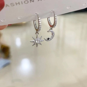 Close-up of asymmetric s925 silver earrings with pavé zircon star and crescent moon pendants