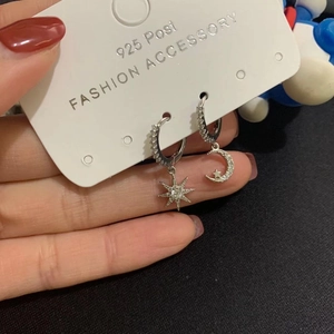 Detail of asymmetric star and moon earrings with 925 silver post and sparkling zircons