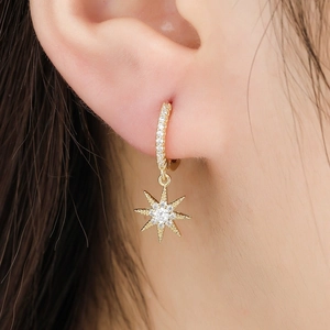 Close-up of star-shaped gold earrings with sparkling pave-set zircons on model ear