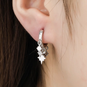 Detail view of silver 925 star dangle earrings worn, featuring minimalist hoop and star charms
