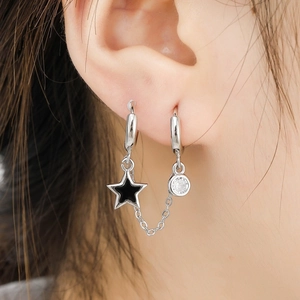 Detail of silver double piercing chain earrings with black star pendant and zircon crystal