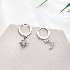 Macro shot of silver S925 moon and star earrings with pavé stones on grey stone base