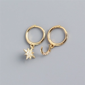 Detailed view of asymmetric gold star and moon earrings with sparkling white zircons