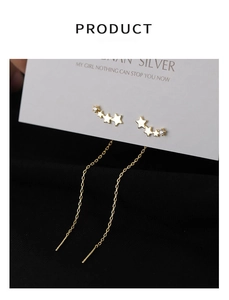 Detailed macro view of golden star earrings with small zircon stones and long chains