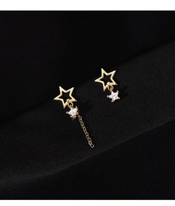 Detailed close-up of asymmetric gold star earrings with sparkling crystals on black fabric