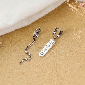 Detailed close-up of asymmetrical S925 silver earrings with vintage chain and letter plaque