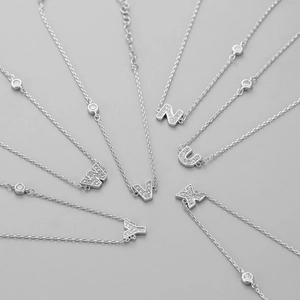 Detailed close-up of micro-paved cubic zirconia letter pendants with adjustable silver chain