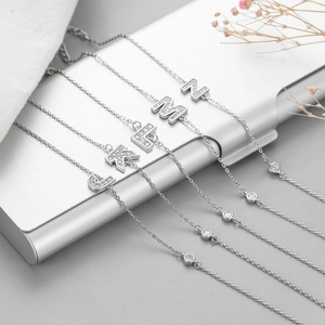 Detail of five-piece minimalist bracelet set with sparkling zircon letter pendants J-N