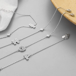 Close-up of silver bracelets with micro-paved zircon initial charms and lobster clasp