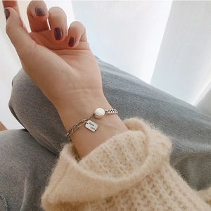 925 Silberarmband mit Good Luck Anhänger und weißer Perle am Handgelenk getragen