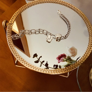 Detail eines S925 Silberarmbands mit Good Luck Anhänger auf einem Spiegeltablett