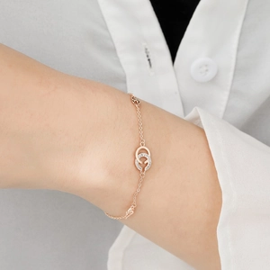 Detailed view of a rose gold double-G interlocking charm bracelet with micro-pave crystals
