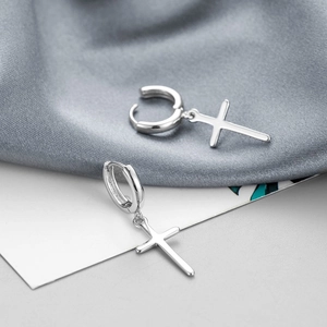 Close-up of S925 silver cross hoop earrings displayed on elegant grey satin background