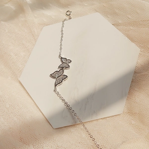 Macro detail of silver butterfly bracelet with sparkling zircon wings on marble surface