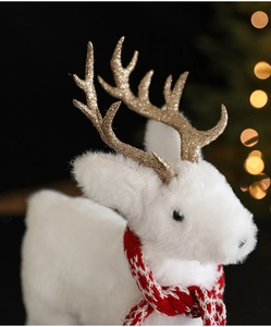 Close-up of white plush Christmas reindeer decoration with a red plaid scarf and gold antlers