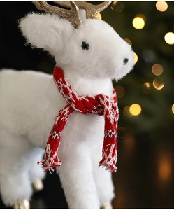 Close-up of white plush Christmas reindeer with red scarf and golden glitter antlers