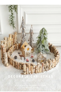 Close-up of a natural birch wood fence with a cozy glowing house and reindeer decor