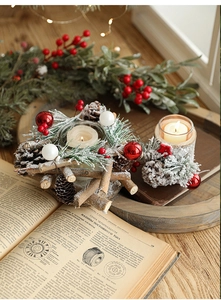 Detail of Christmas candle holder with pine cones, needles, and glass cups on festive table