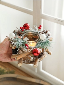 Close-up of a Christmas candle holder with pine cones, red berries, and glass cup
