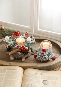 Close-up of Christmas pinecone candle holders with faux snow and lit candles on wood