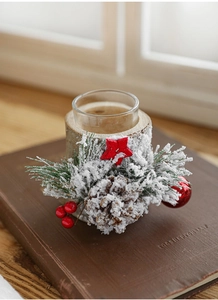 Close-up of rustic Christmas candle holder with pine cones and faux snow on wood