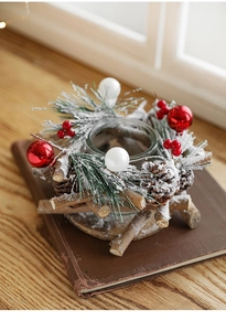 Close-up of snowy pine cone candle holder with red berries on vintage books