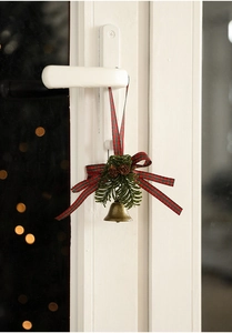 Detail of bronze Christmas bell with pine cones and red-green plaid bow door hanging