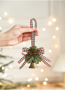 Close-up of bronze metal bell with pine cones and checkered ribbon holiday ornament