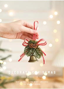 Close-up of bronze metal bell with pine cones, needles and a red-white striped bow