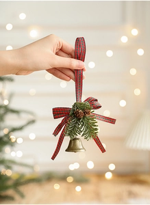 Detail of vintage bronze Christmas bell ornament with pine needles and plaid ribbon bow