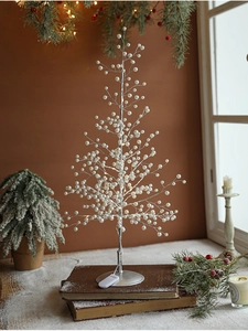 Close-up of pearl LED tree decoration with silver branches on vintage books